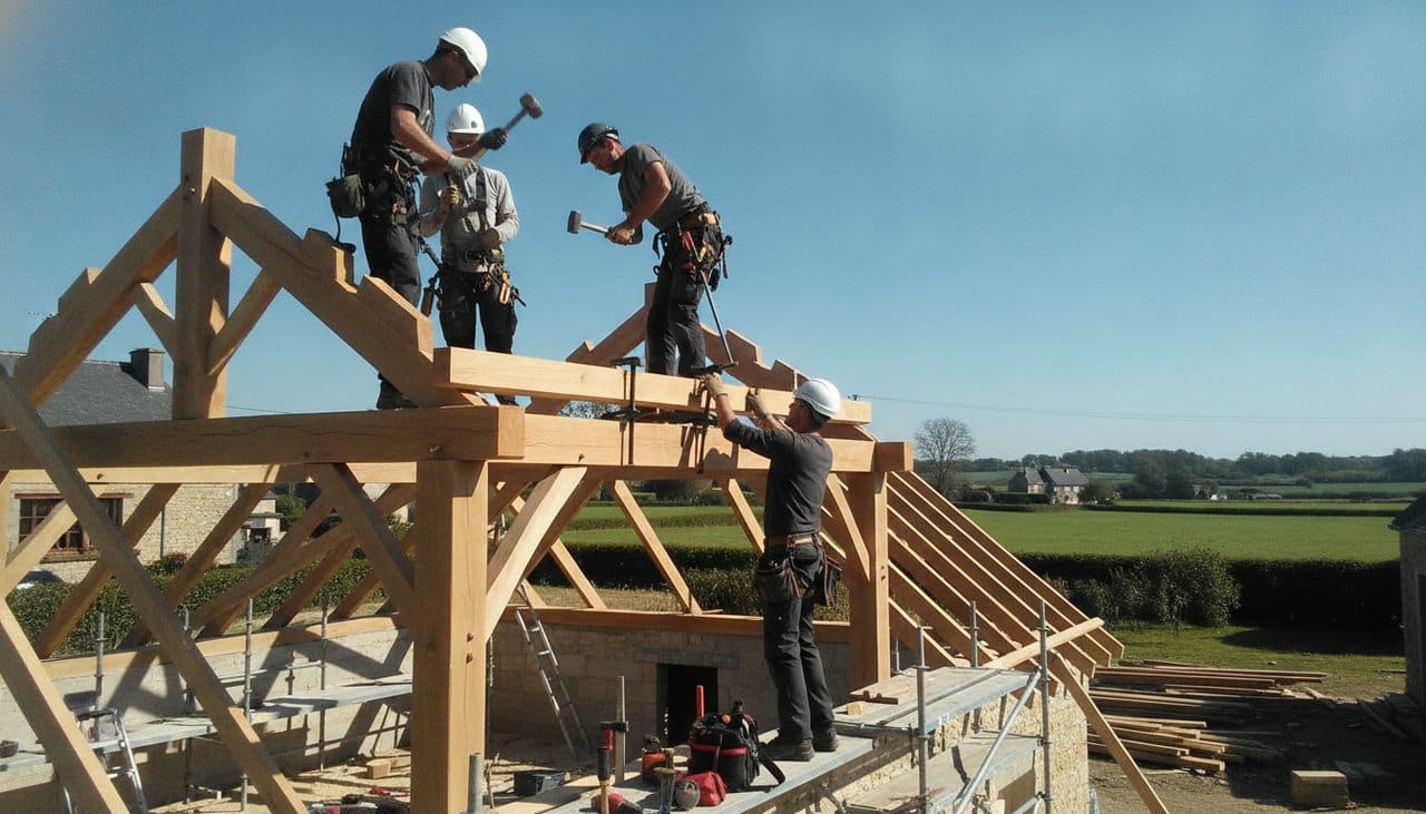 Charpentiers assemblant une charpente traditionnelle en bois sur une extension de maison